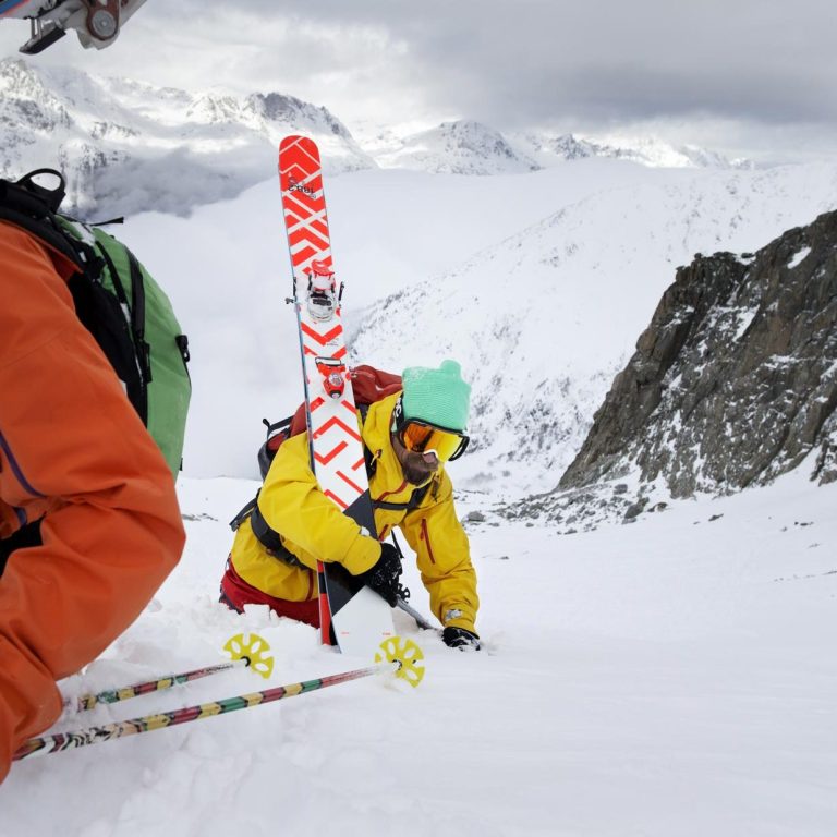 Skieur en montagne, tirant des skis sur la neige, avec un paysage alpin en arrière-plan.